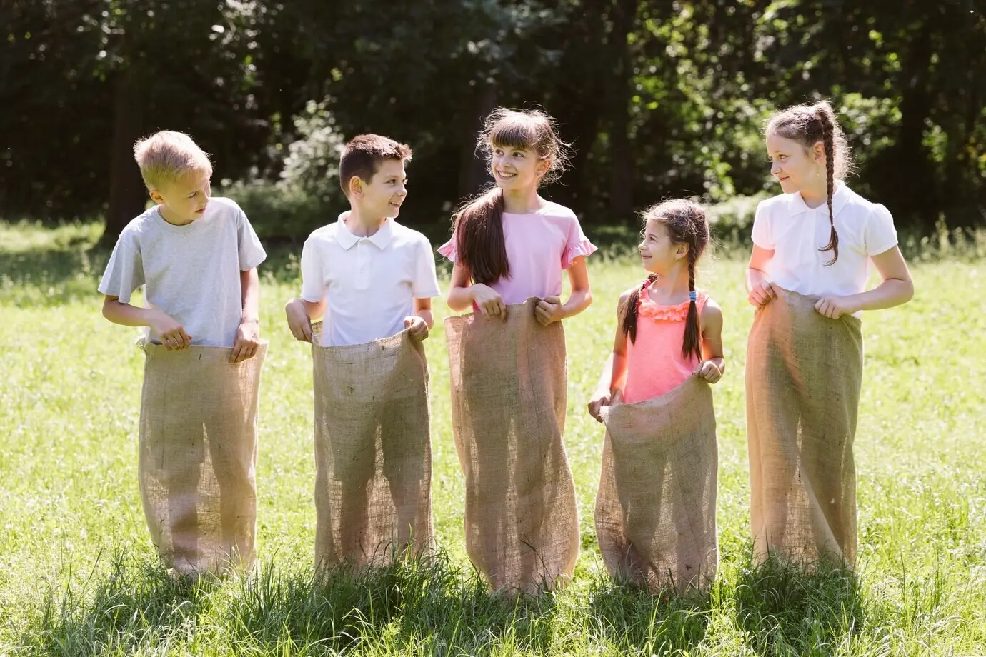 Kinder posieren in Jutesäcken.