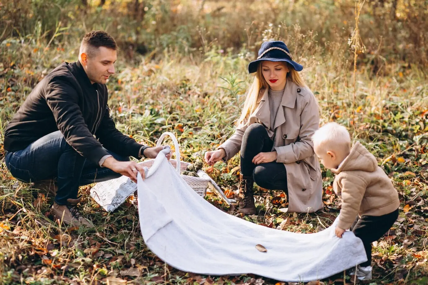 Eine Familie macht ein kleines Picknick mit ihrem Sohn in einem herbstlichen Park.